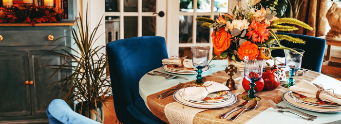 A cozy kitchen with a small table set for four, surrounded by fall-themed decor.