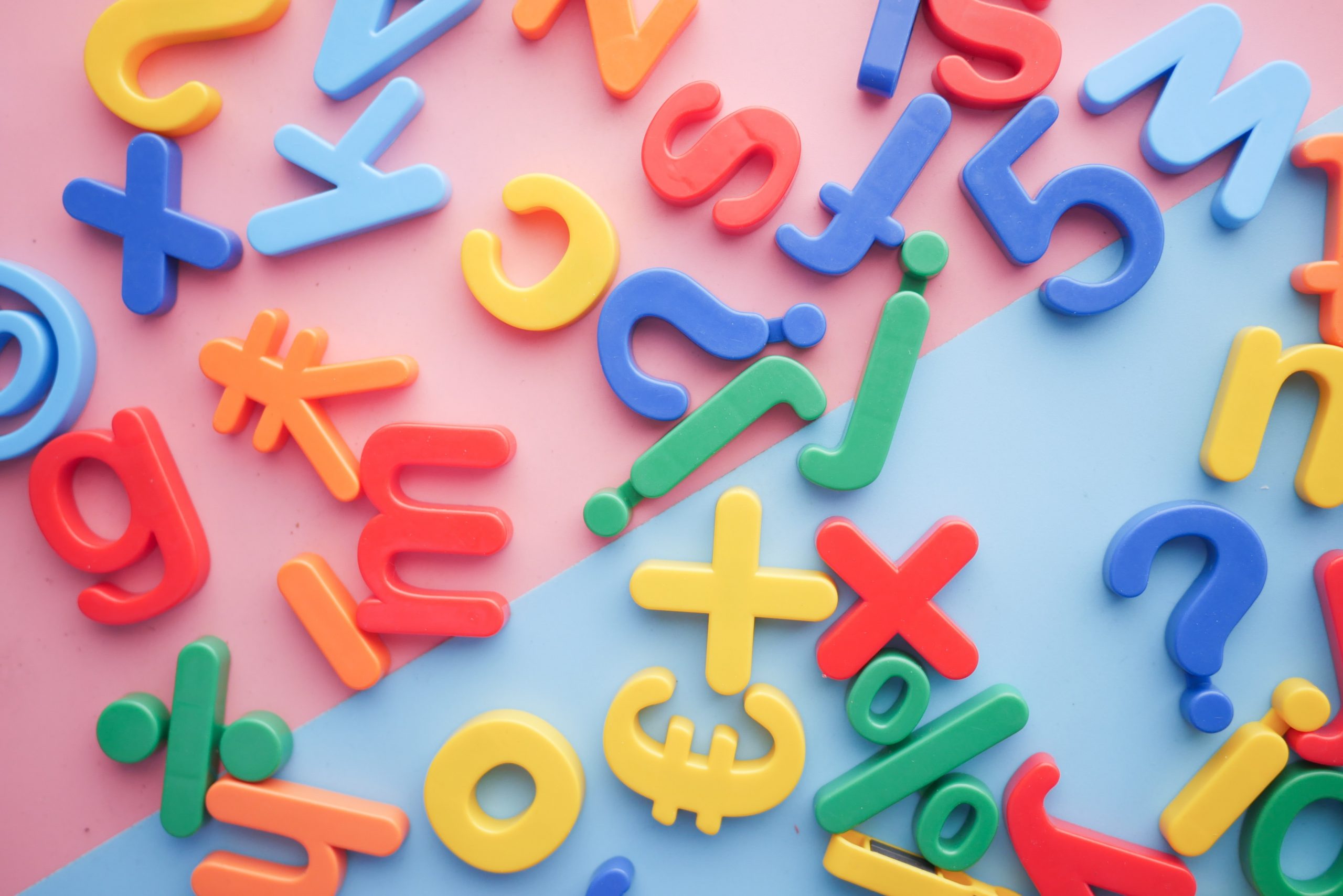 Multicoloured fridge magnets in the shape of the letters of the English alphabet, and English-style punctuation, all jumbled up together in a big mess.
