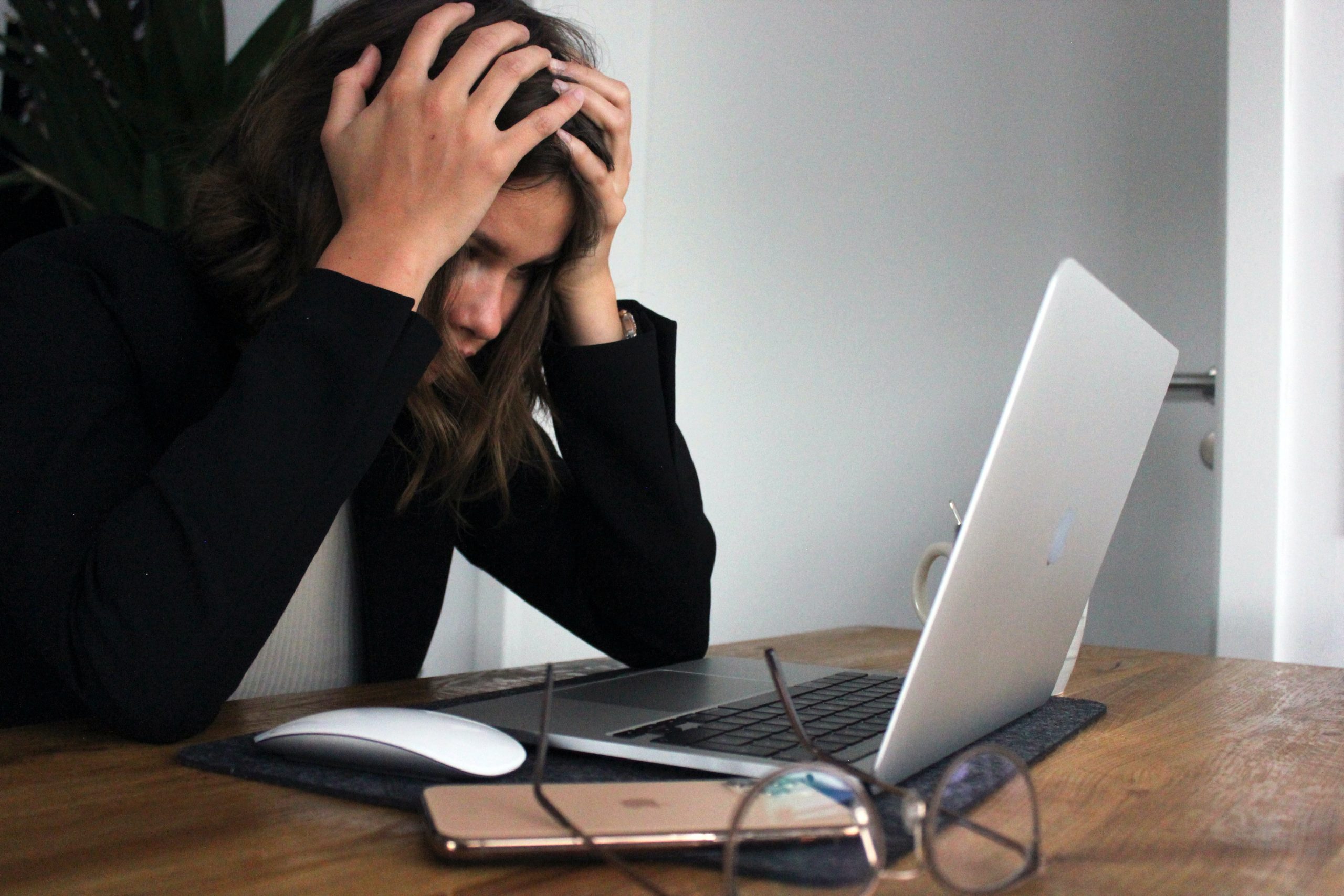 A woman sitting in front of her laptop with her head in her hands, completely exasperated.