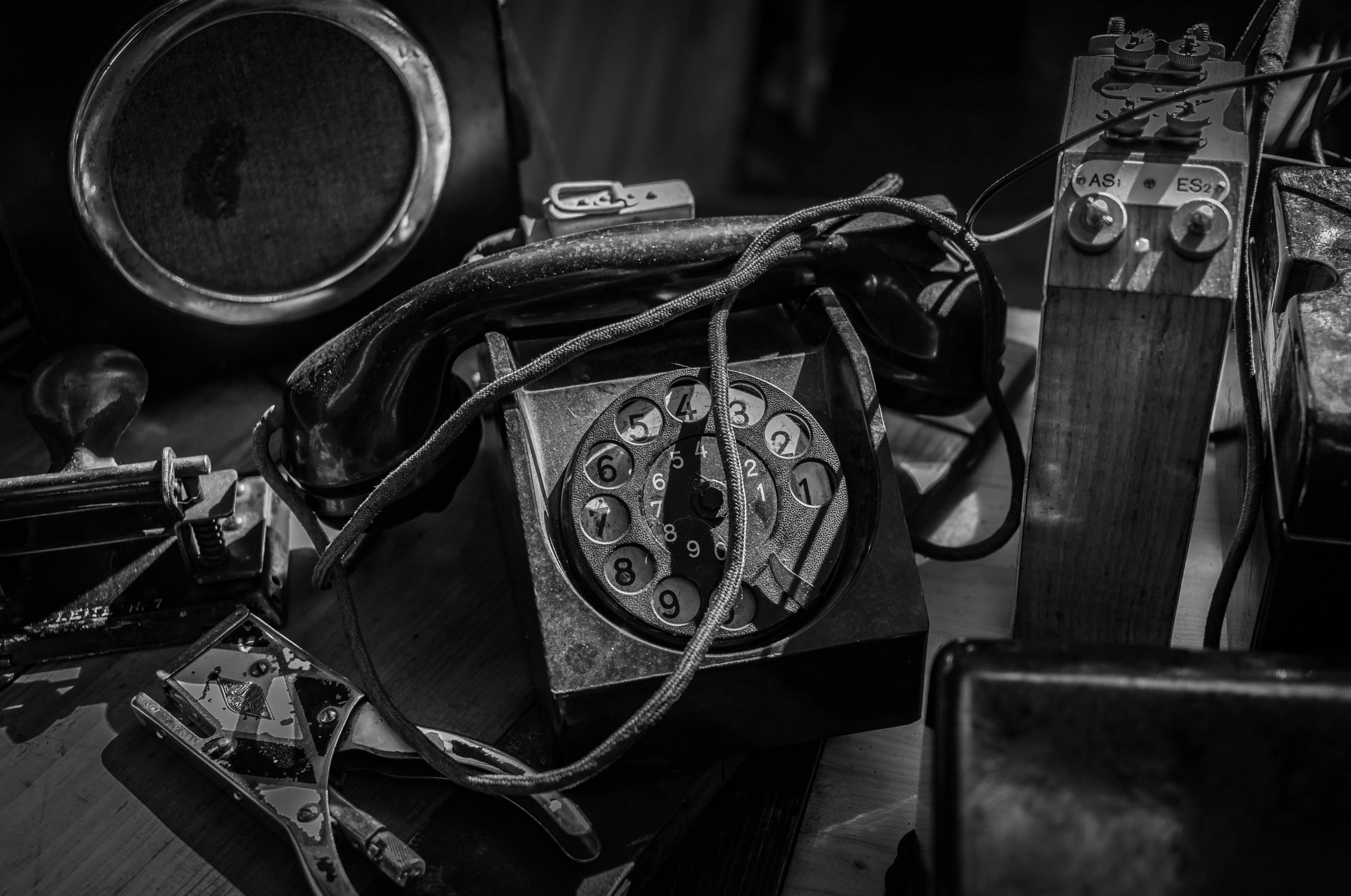 A black and white photo of a bunch of dusty and broken communications equipment.