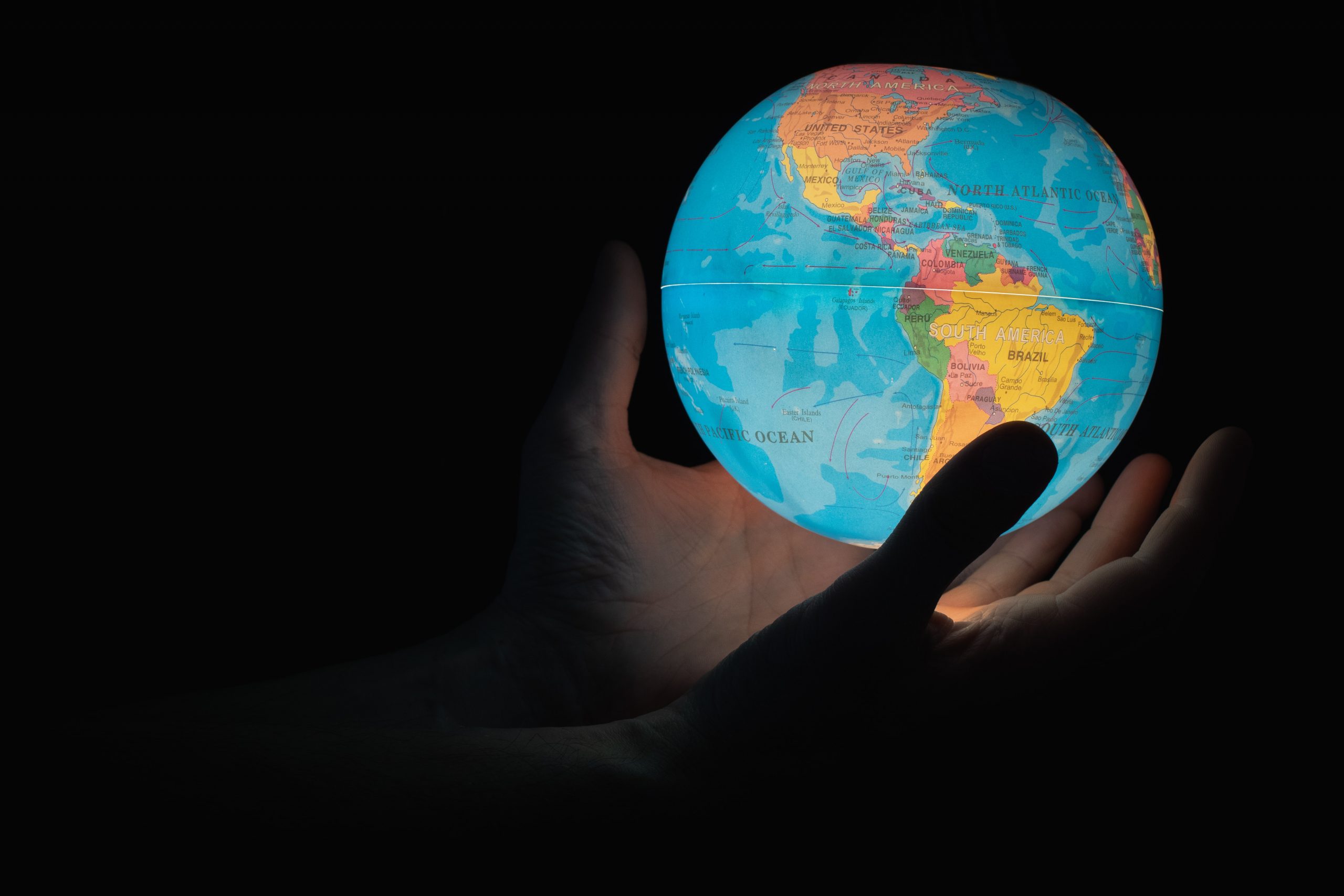 A pair of hands holding a glowing planet Earth.