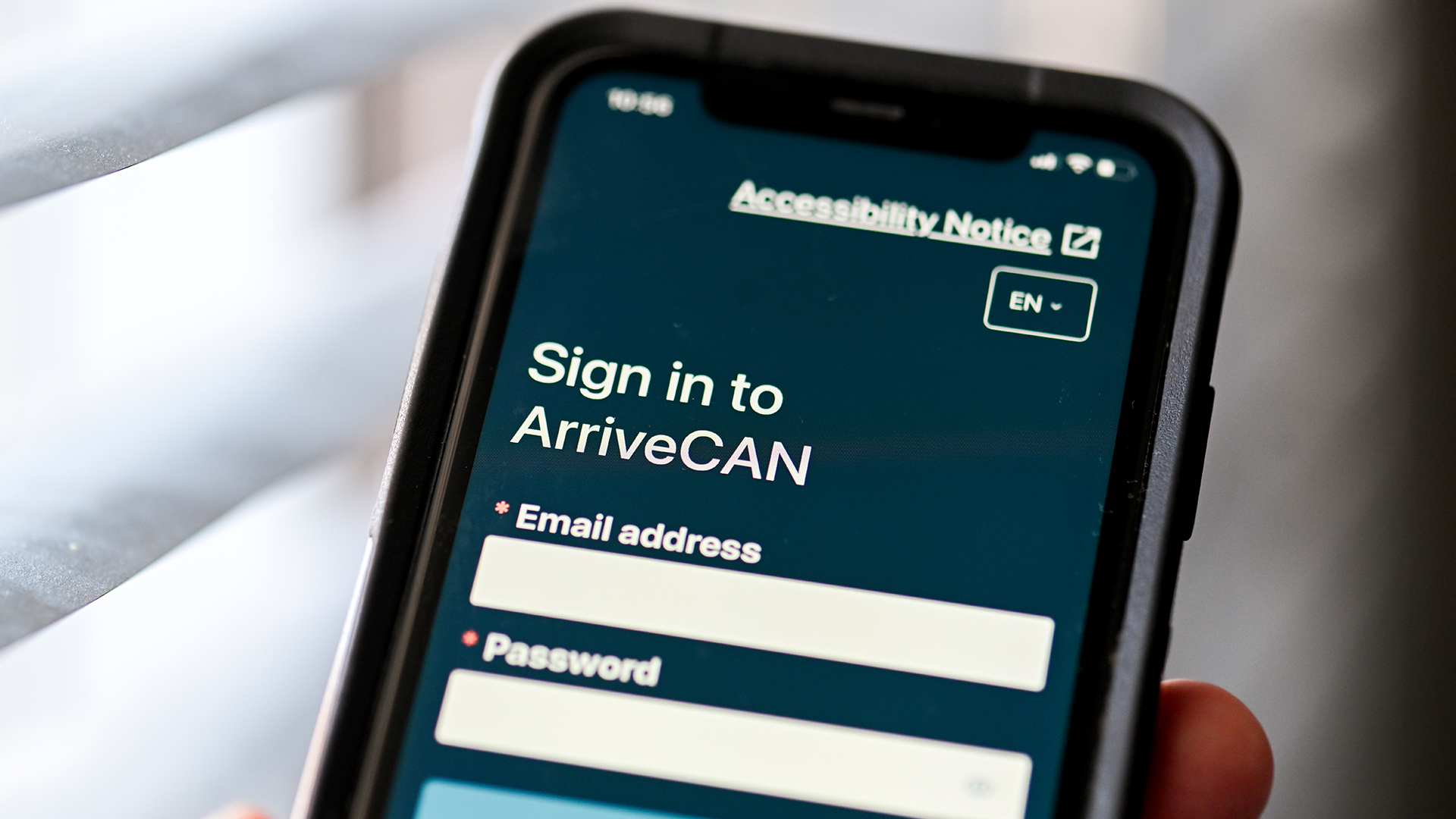 A photo of a smartphone with the ArriveCan app visible as it waits for login credentials.