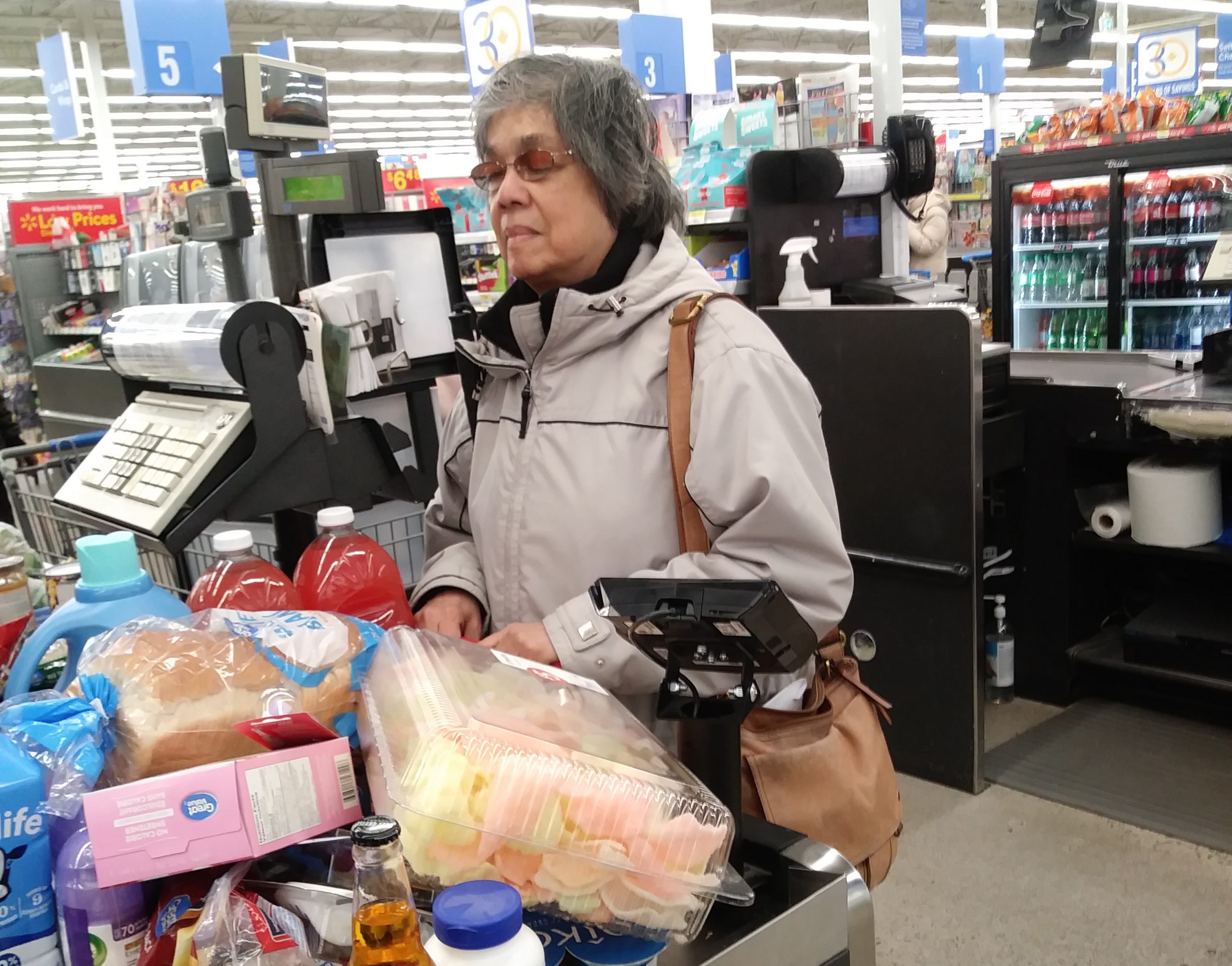 Donna standing at the cash at Walmart with lots of groceries in front of her.