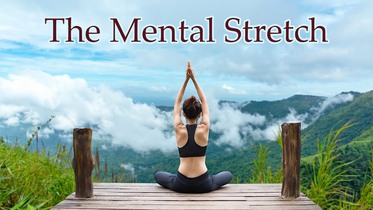 A photo of a woman seated on a dock with her back to the camera. She is doing a seated yoga pose against a serene backdrop of mountains, trees, and clouds.