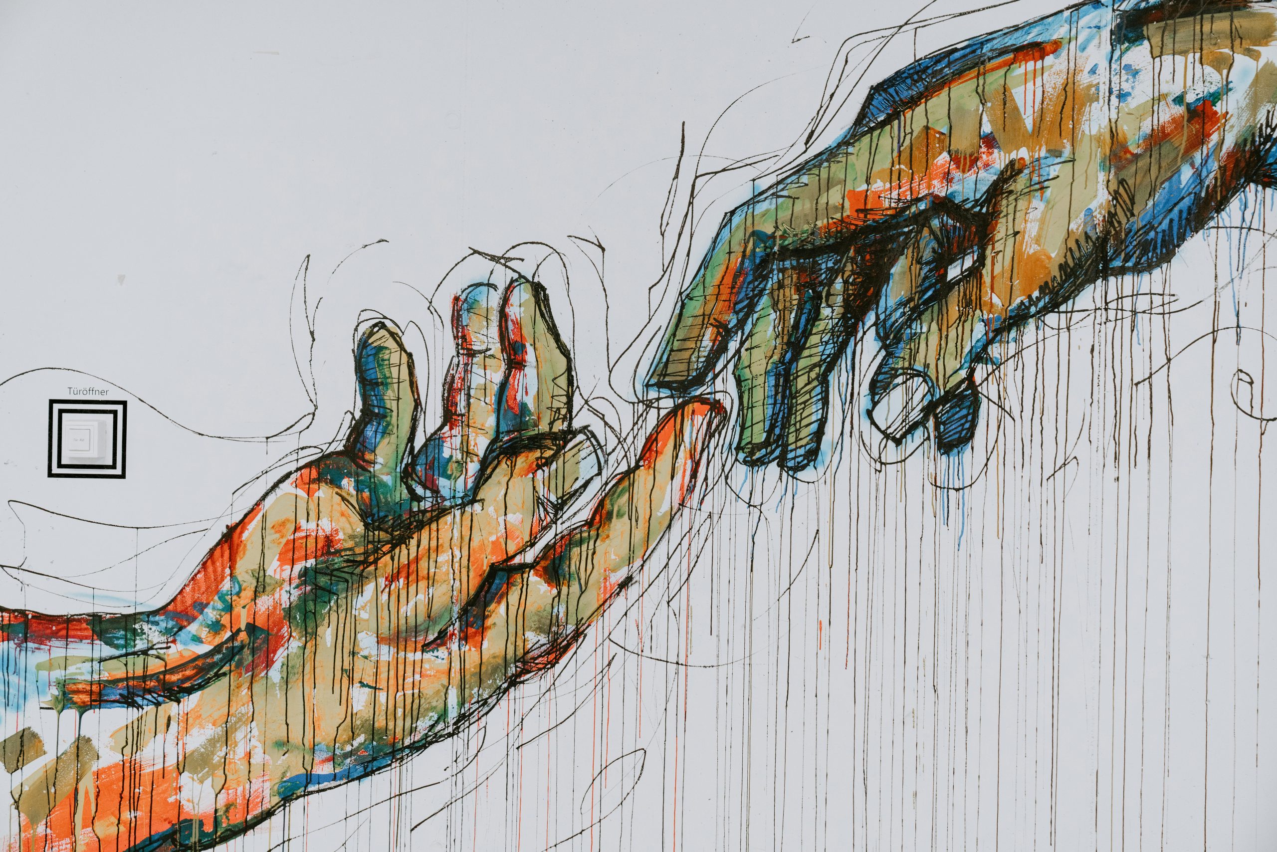 A colourful painting of two hands reaching out to each other, their fingertips just touching.