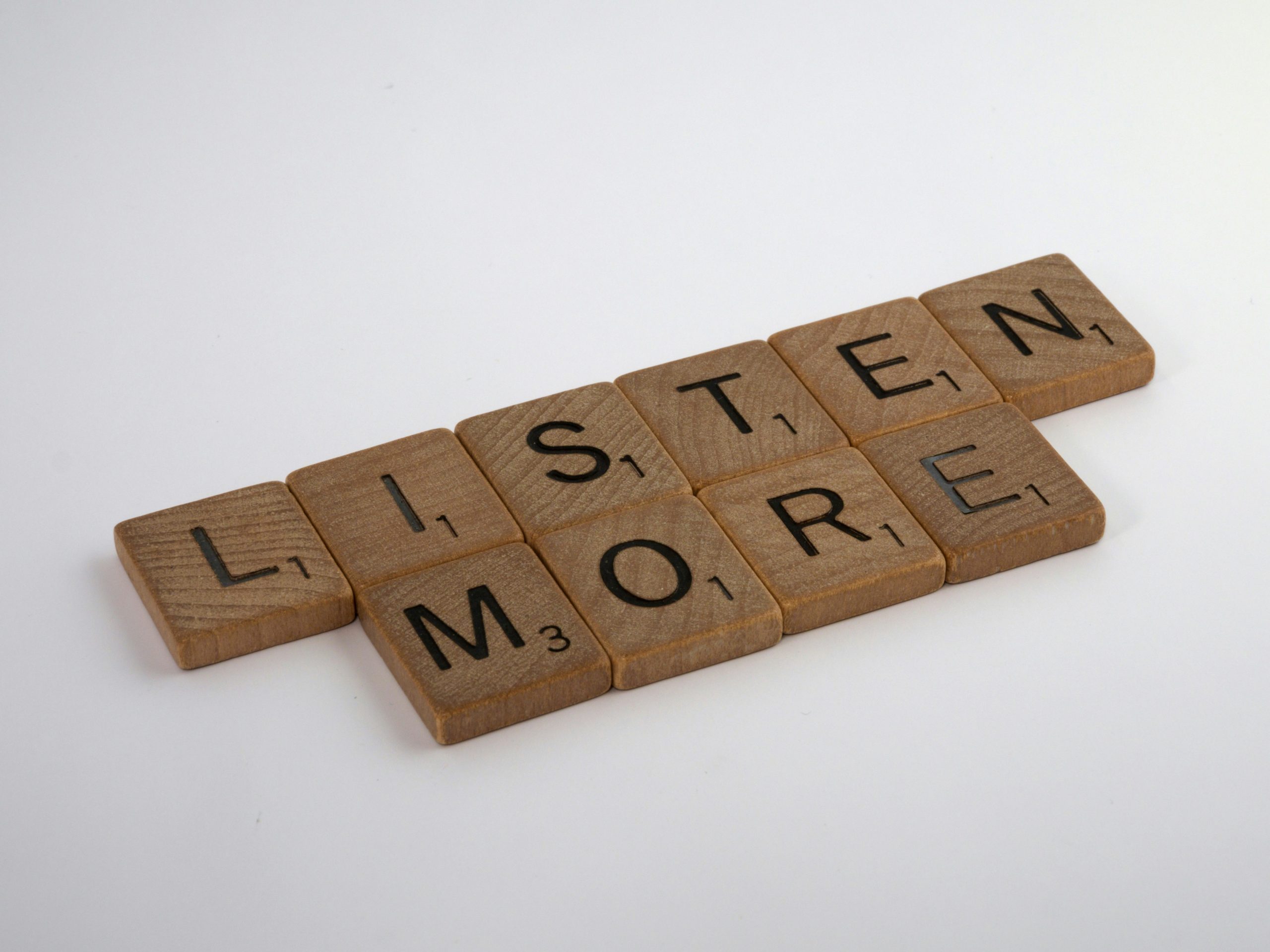 An image of Scrabble tiles arranged to say "Listen more."