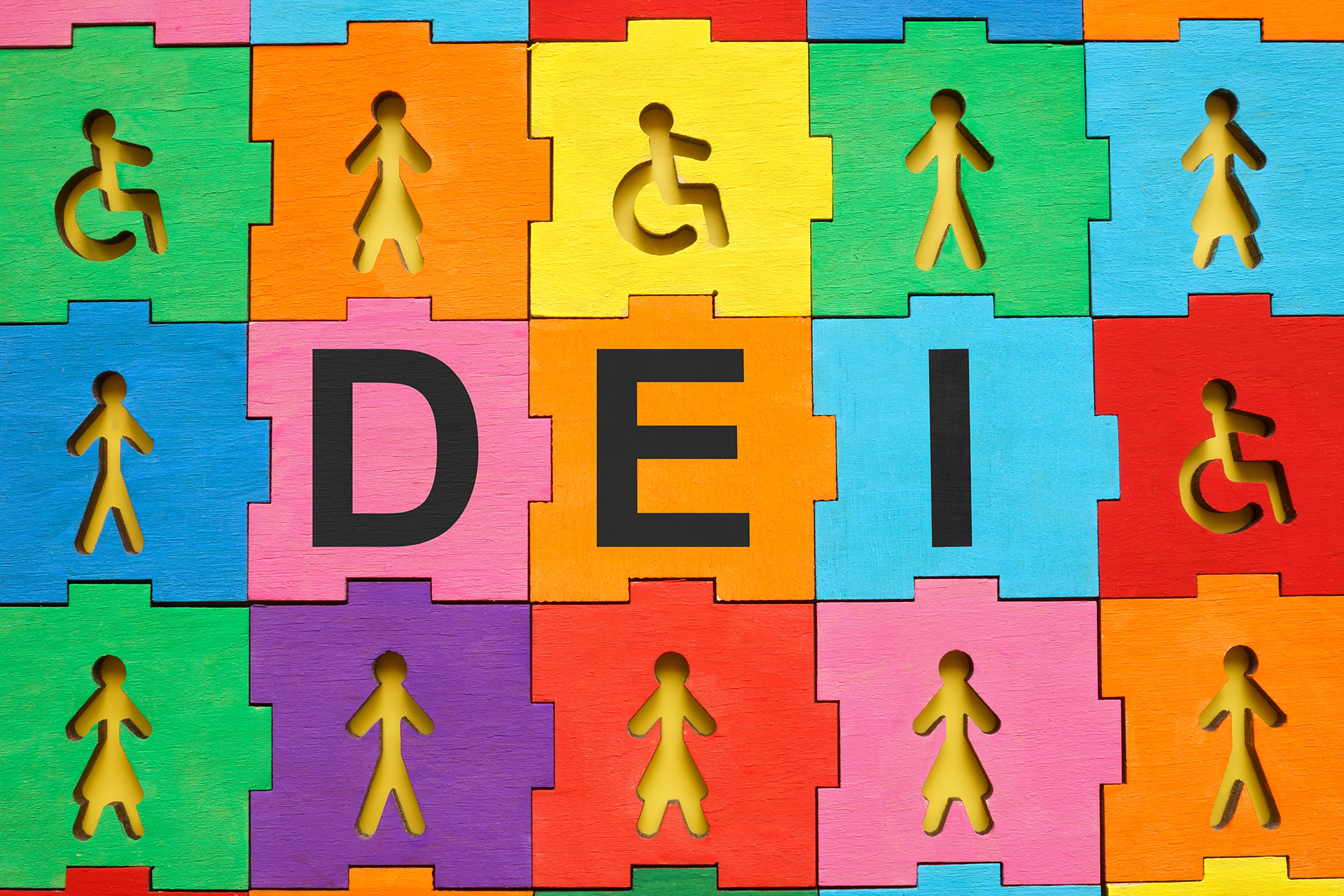 A colorful puzzle-like background features interlocking wooden pieces in bright shades of blue, green, yellow, orange, pink, purple, and red. Some pieces have cut-out silhouettes of diverse human figures, including individuals walking, figures in dresses, and wheelchair users, symbolizing inclusivity. The bold black letters 'D,' 'E,' and 'I' are prominently displayed in the center, representing Diversity, Equity, and Inclusion. The vibrant composition visually reinforces the theme of unity and representation.