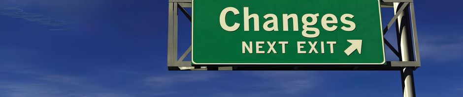 A green highway sign mounted on a tall metal pole reads 'Changes' in large white letters, with 'Next Exit' and a right-pointing arrow below it, set against a clear blue sky with wispy clouds.
