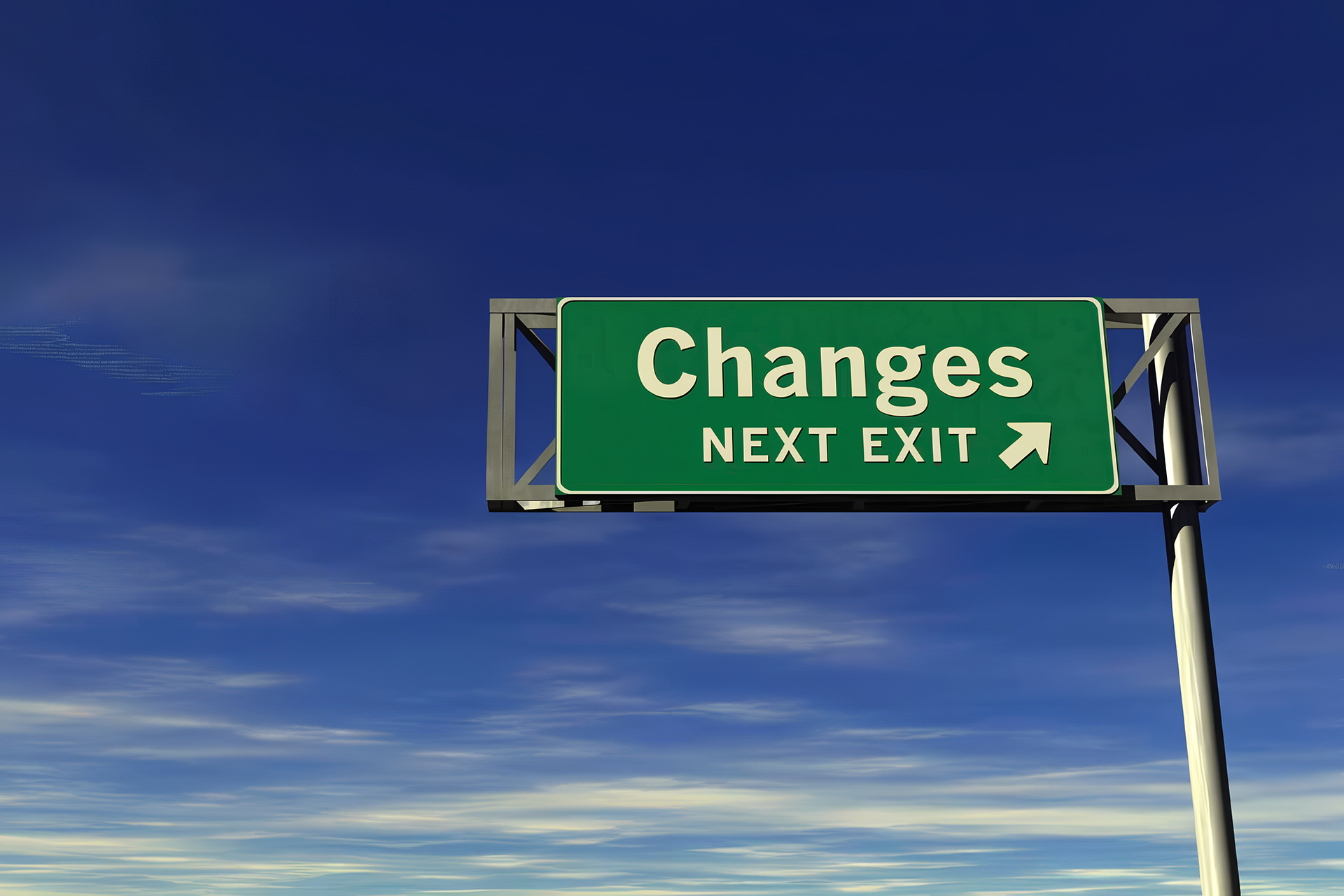 A green highway sign mounted on a tall metal pole reads 'Changes' in large white letters, with 'Next Exit' and a right-pointing arrow below it, set against a clear blue sky with wispy clouds.
